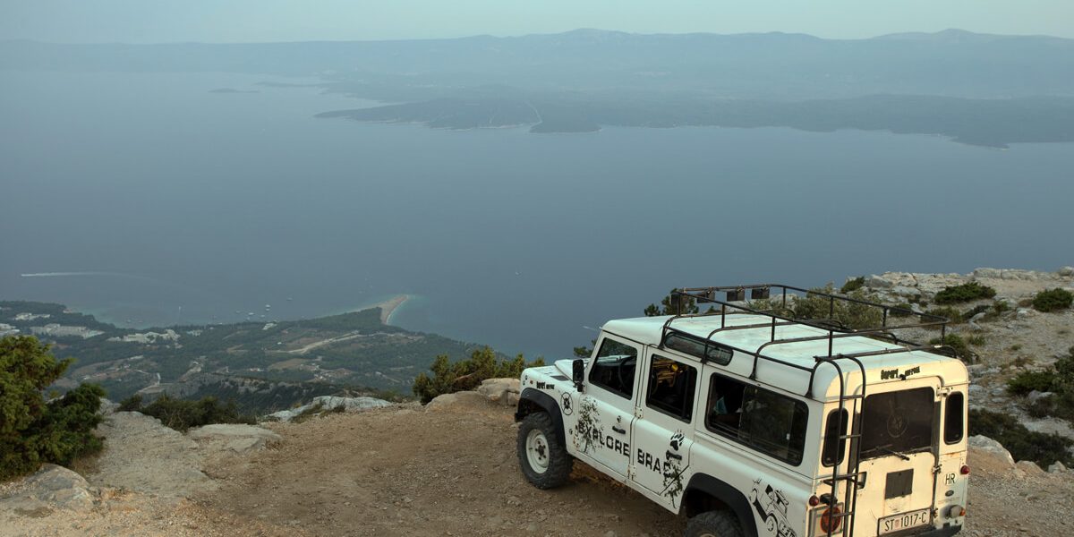 Parked Land Rover on Vidova gora, in the long distance seaside & Zlatni rat, Brac island
